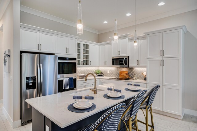 kitchen with appliances with stainless steel finishes, sink, a center island with sink, and backsplash