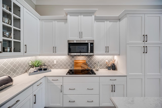 kitchen featuring white cabinetry, black electric cooktop, tasteful backsplash, and light stone counters