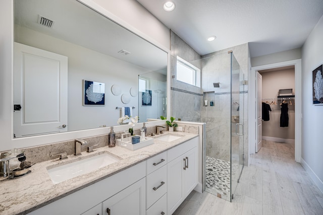 bathroom with hardwood / wood-style floors, walk in shower, and vanity