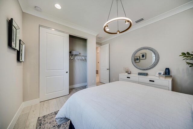 bedroom featuring a closet, light hardwood / wood-style flooring, and crown molding