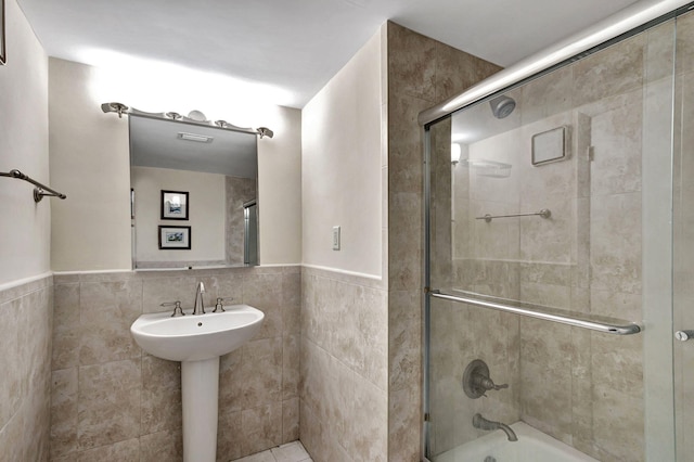 bathroom featuring tile walls, backsplash, and bath / shower combo with glass door