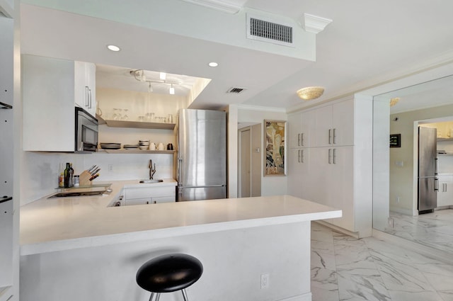 kitchen with appliances with stainless steel finishes, kitchen peninsula, sink, and a breakfast bar