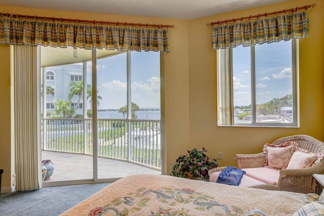 carpeted bedroom with multiple windows, access to exterior, and a water view