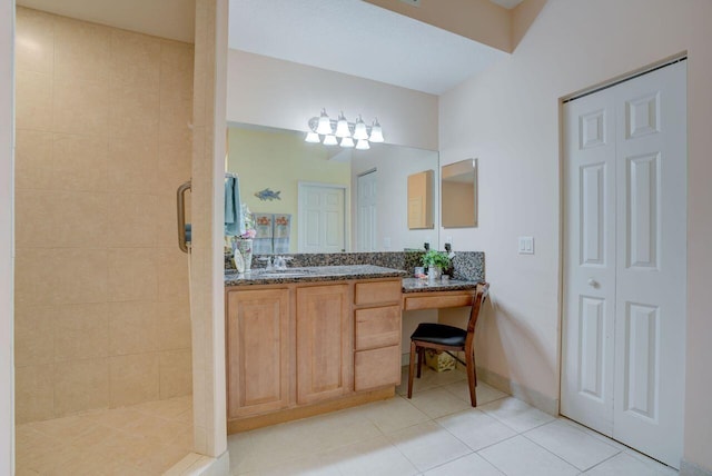 bathroom with a tile shower, vanity, and tile patterned flooring