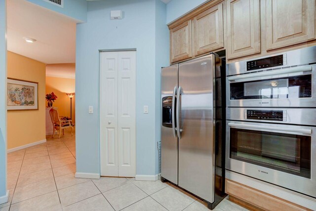 kitchen with light tile patterned floors, stainless steel appliances, and light brown cabinetry