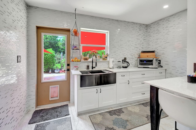 kitchen featuring light tile patterned flooring, sink, and white cabinets