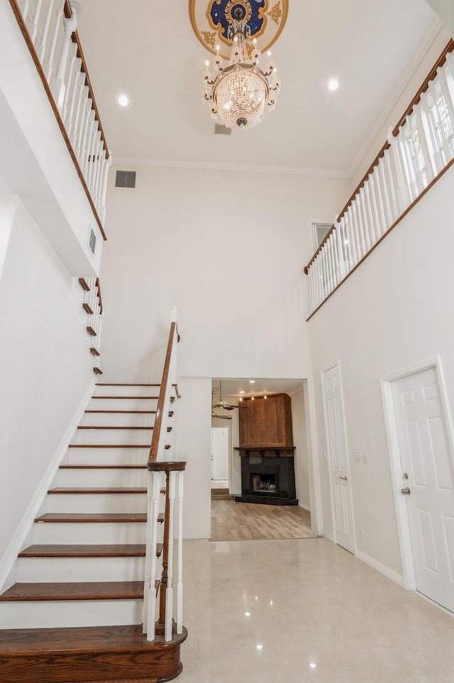 staircase featuring crown molding, an inviting chandelier, and a towering ceiling