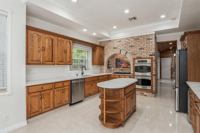 kitchen featuring a textured ceiling, appliances with stainless steel finishes, a center island, ornamental molding, and sink