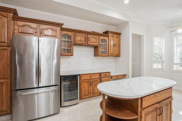 kitchen featuring a center island, stainless steel refrigerator, beverage cooler, tasteful backsplash, and ornamental molding