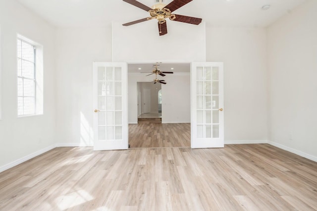 empty room with light hardwood / wood-style flooring, ceiling fan, and french doors