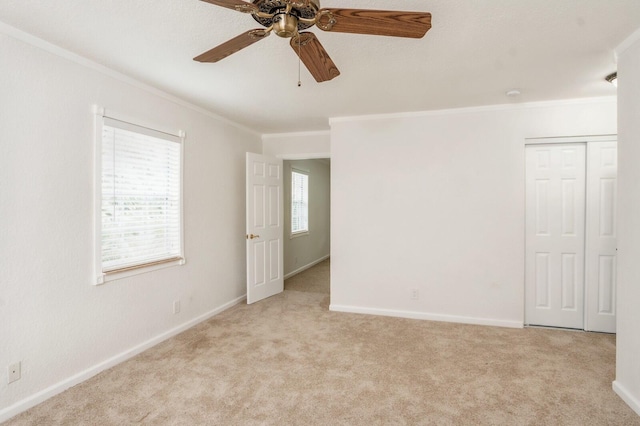 carpeted spare room featuring ornamental molding, plenty of natural light, and ceiling fan