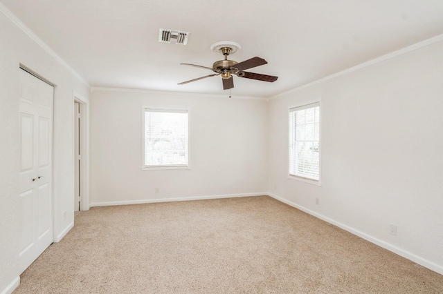 carpeted spare room featuring ceiling fan, a wealth of natural light, and crown molding