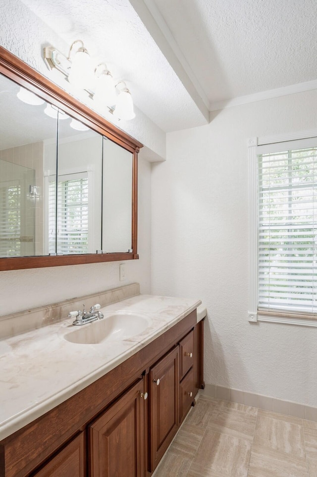 bathroom featuring a shower with door, vanity, a healthy amount of sunlight, and a textured ceiling