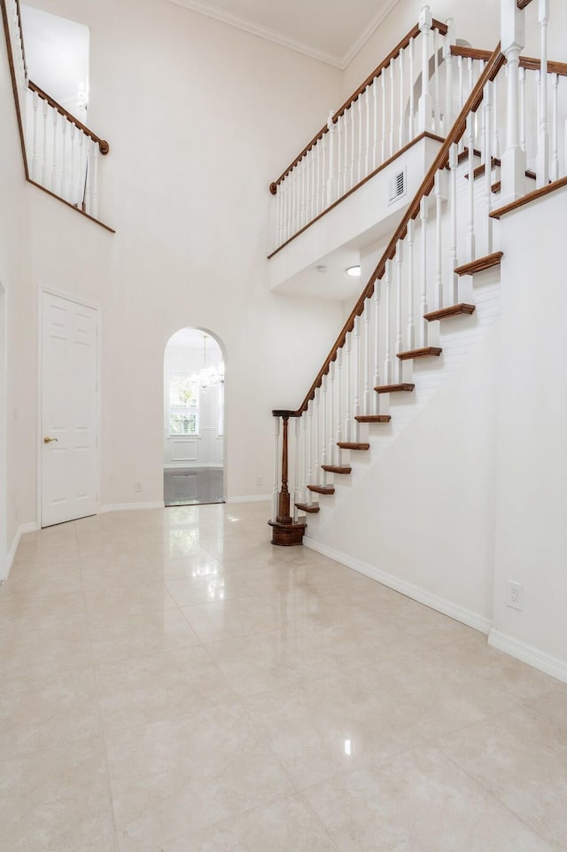 entryway with crown molding and a towering ceiling