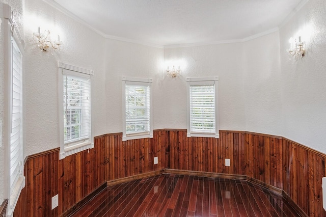 unfurnished room featuring crown molding, wood walls, and hardwood / wood-style floors