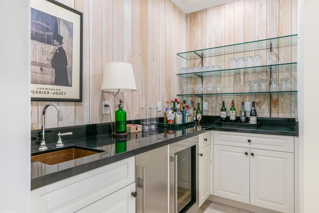 bar featuring beverage cooler, white cabinets, and sink