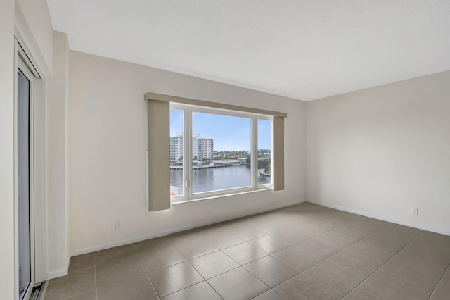 unfurnished room featuring a water view and light tile patterned floors