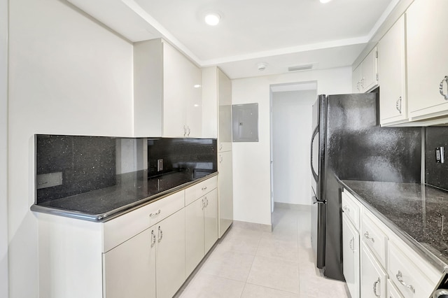 kitchen featuring light tile patterned floors, electric panel, tasteful backsplash, and white cabinetry