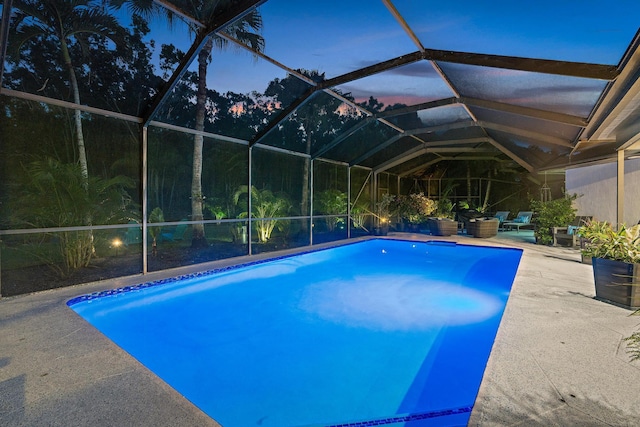 pool at dusk featuring a lanai and a patio