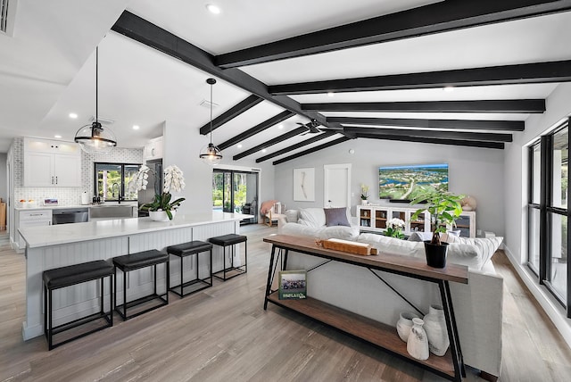 living room with sink, light wood-type flooring, and vaulted ceiling with beams