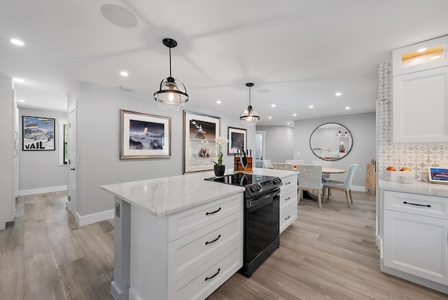 kitchen with light stone countertops, pendant lighting, light hardwood / wood-style floors, electric range, and white cabinets