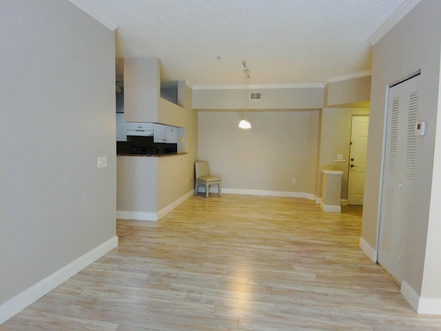 unfurnished living room featuring a textured ceiling, ornamental molding, and light hardwood / wood-style floors