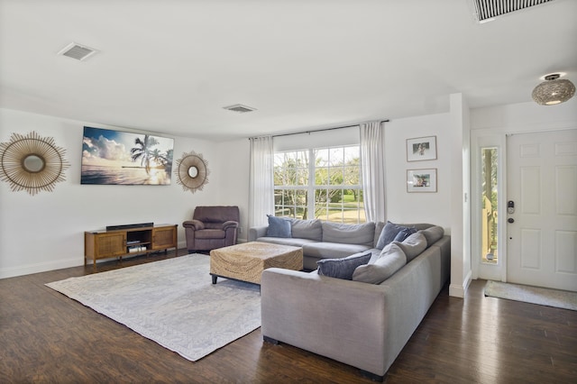 living area featuring dark wood-style flooring, visible vents, and baseboards