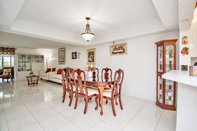 tiled dining area featuring a tray ceiling