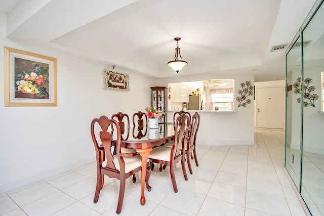 dining area featuring ceiling fan, a raised ceiling, and light tile patterned flooring