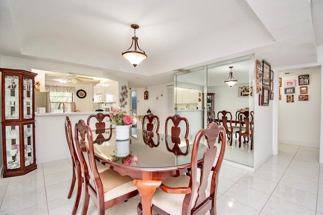 tiled dining room featuring a tray ceiling and ceiling fan