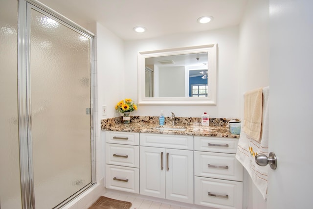 bathroom with a shower with shower door, vanity, and tile patterned flooring