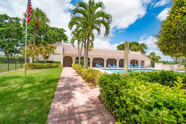 view of front facade featuring a front yard and a fenced in pool