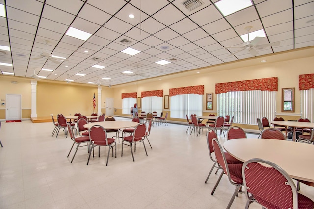 dining area featuring a paneled ceiling, light tile patterned floors, ornate columns, and ceiling fan