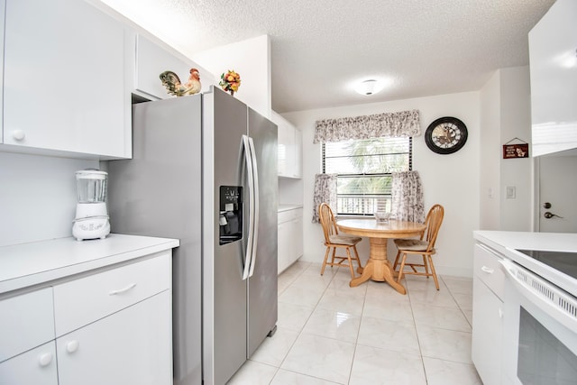 kitchen featuring light tile patterned flooring, stainless steel refrigerator with ice dispenser, a textured ceiling, and white cabinetry