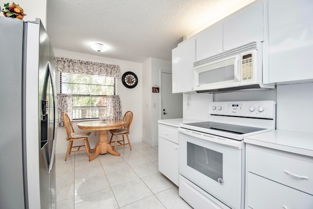 kitchen with white appliances, white cabinets, a textured ceiling, and light tile patterned floors