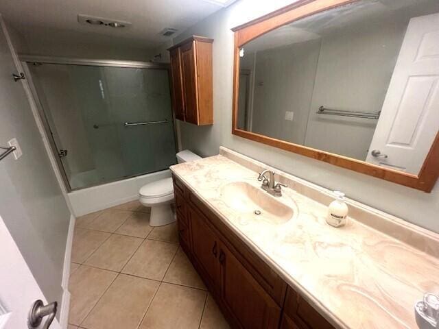 full bathroom with toilet, tile patterned floors, vanity, and bath / shower combo with glass door