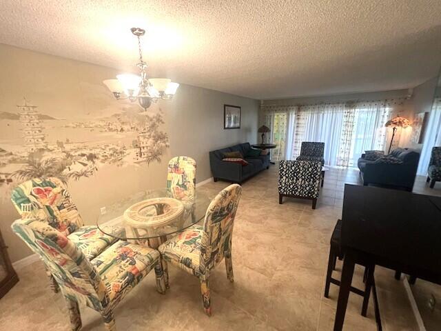 dining space featuring light tile patterned flooring, a textured ceiling, and an inviting chandelier