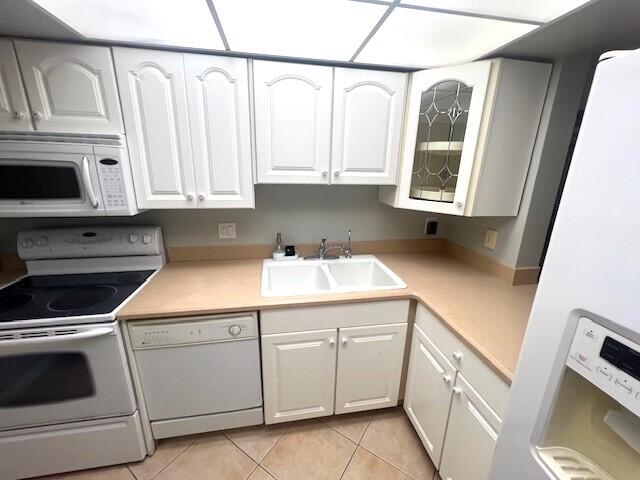 kitchen featuring white appliances, sink, white cabinetry, and light tile patterned floors