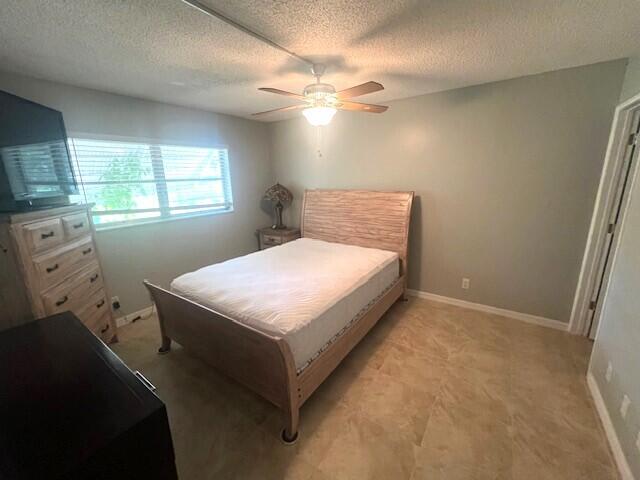 tiled bedroom featuring ceiling fan and a textured ceiling