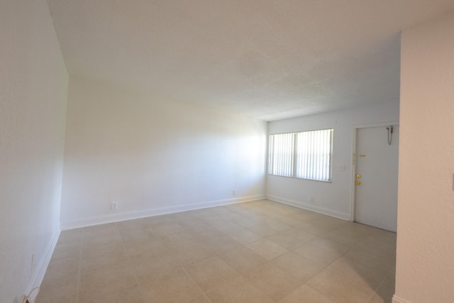 spare room with light tile patterned flooring and a textured ceiling