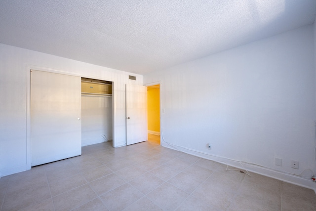 unfurnished bedroom featuring light tile patterned flooring, a textured ceiling, and a closet