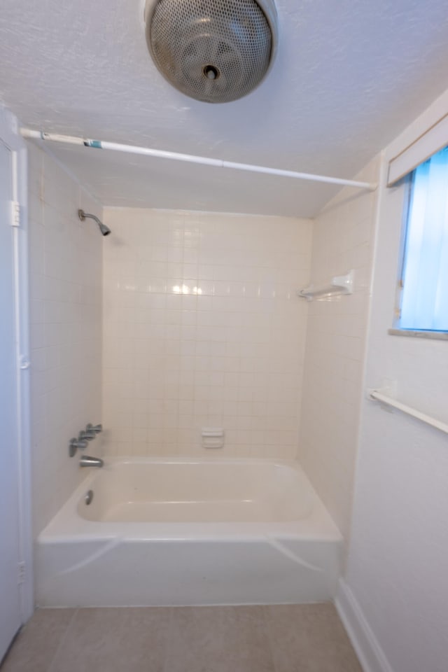 bathroom with tiled shower / bath combo and tile patterned flooring