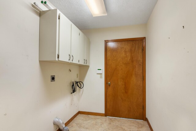 washroom with a textured ceiling, light tile patterned floors, cabinets, and hookup for an electric dryer