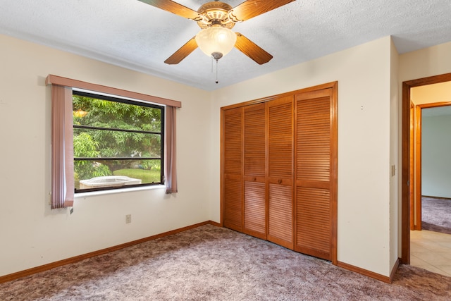 unfurnished bedroom with a textured ceiling, a closet, ceiling fan, and light colored carpet