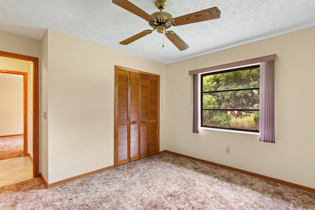 unfurnished bedroom featuring ceiling fan, light colored carpet, a closet, and a textured ceiling