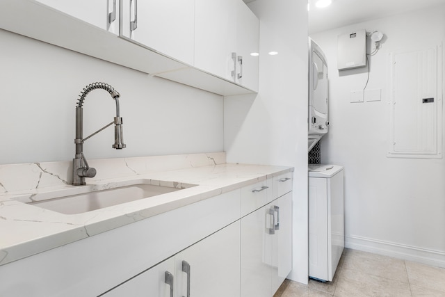 washroom with cabinets, stacked washer and dryer, sink, electric panel, and light tile patterned flooring