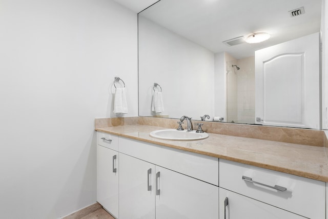 bathroom featuring tiled shower and vanity