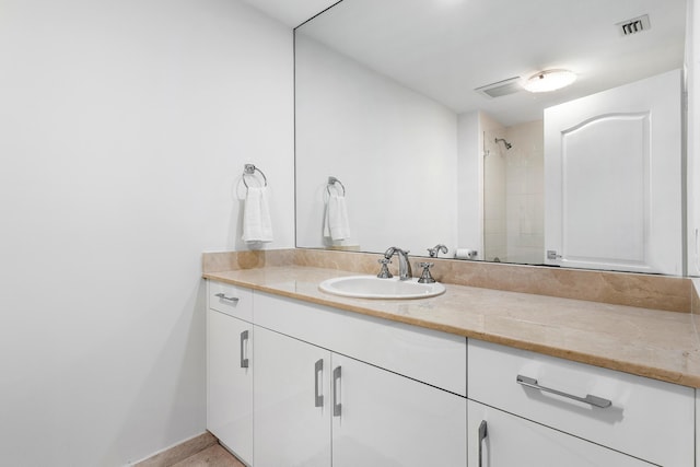 full bathroom featuring baseboards, visible vents, tiled shower, and vanity