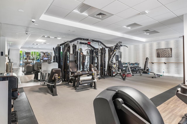 exercise room featuring visible vents, a drop ceiling, and carpet flooring