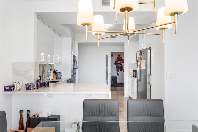 kitchen with backsplash, stainless steel appliances, decorative light fixtures, kitchen peninsula, and sink